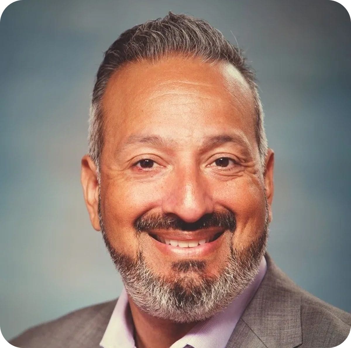 Smiling man with beard and suit jacket.