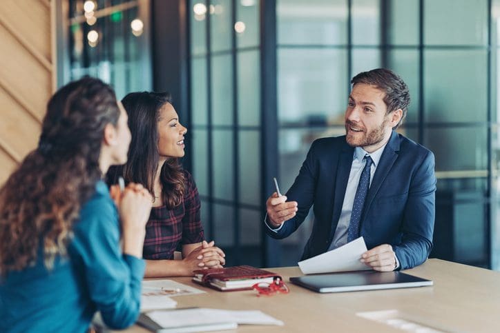 Business meeting with three people discussing documents.