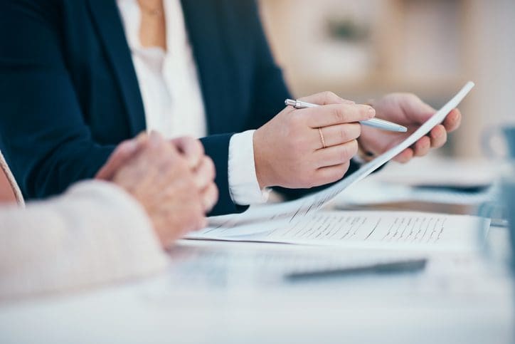Two people reviewing documents at desk.