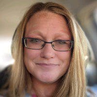 Smiling person with glasses in a car.