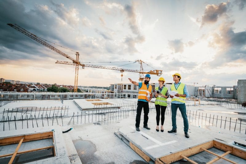 Construction workers planning on building site rooftop.