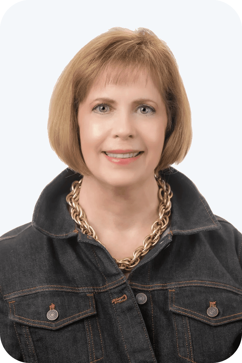 Smiling woman in denim jacket and necklace.